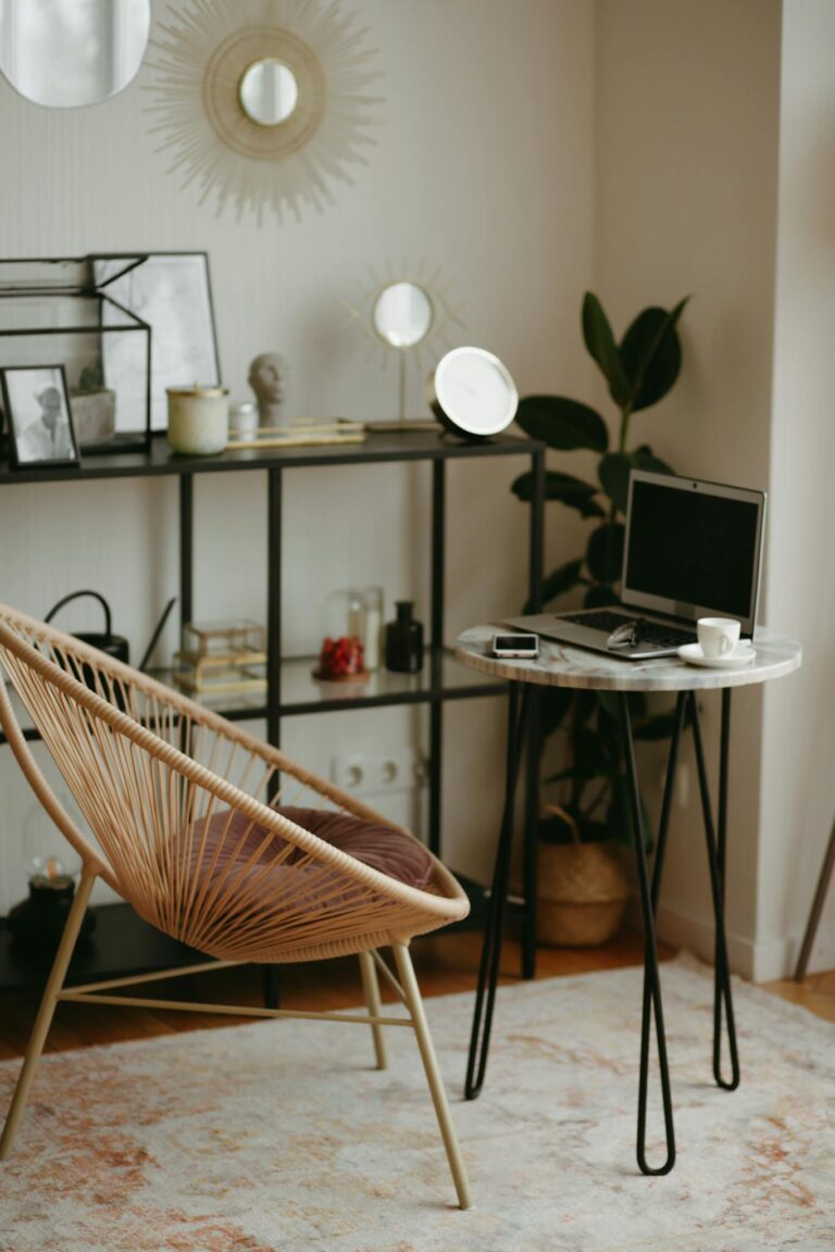 A modern home office with a laptop, stylish chair, shelves, and decor for a cozy work-from-home setup.